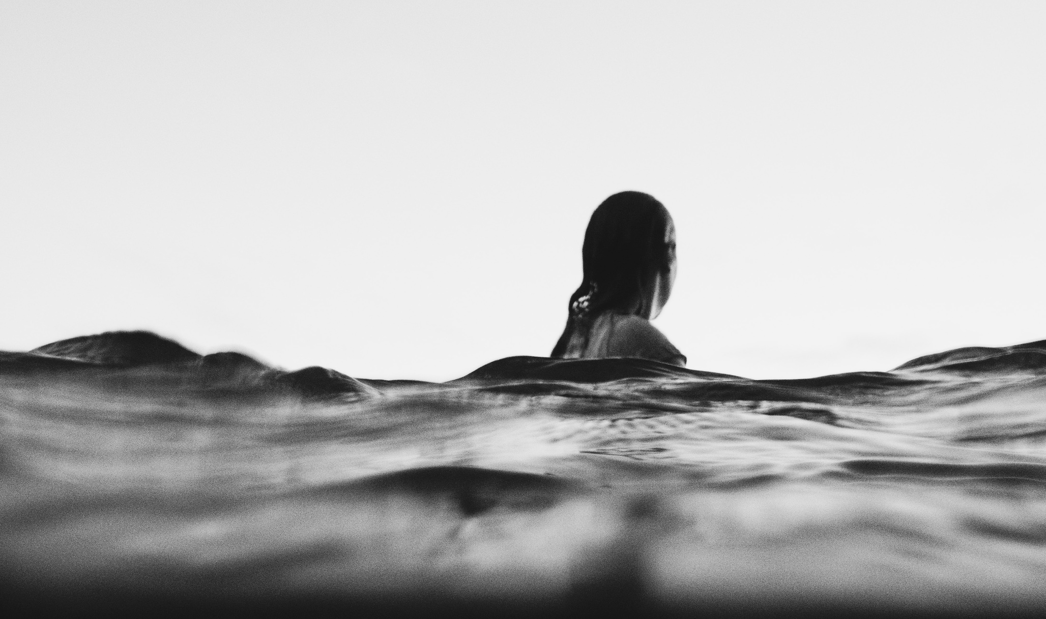 Woman laying on surfboard looking away from the camera